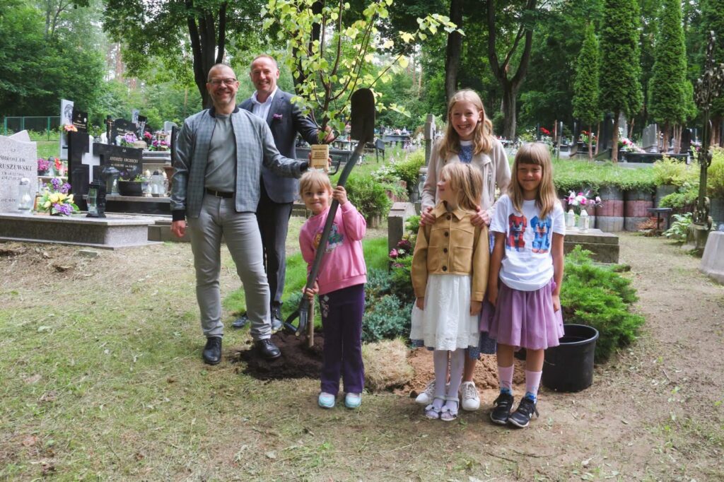 Rodzina sadząca drzewo na cmentarzu