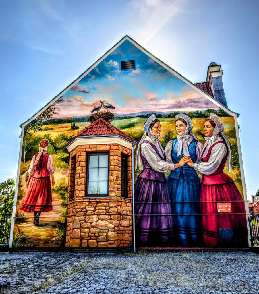 Mural przedstawiający trzy kobiety w tradycyjnych strojach ludowych.