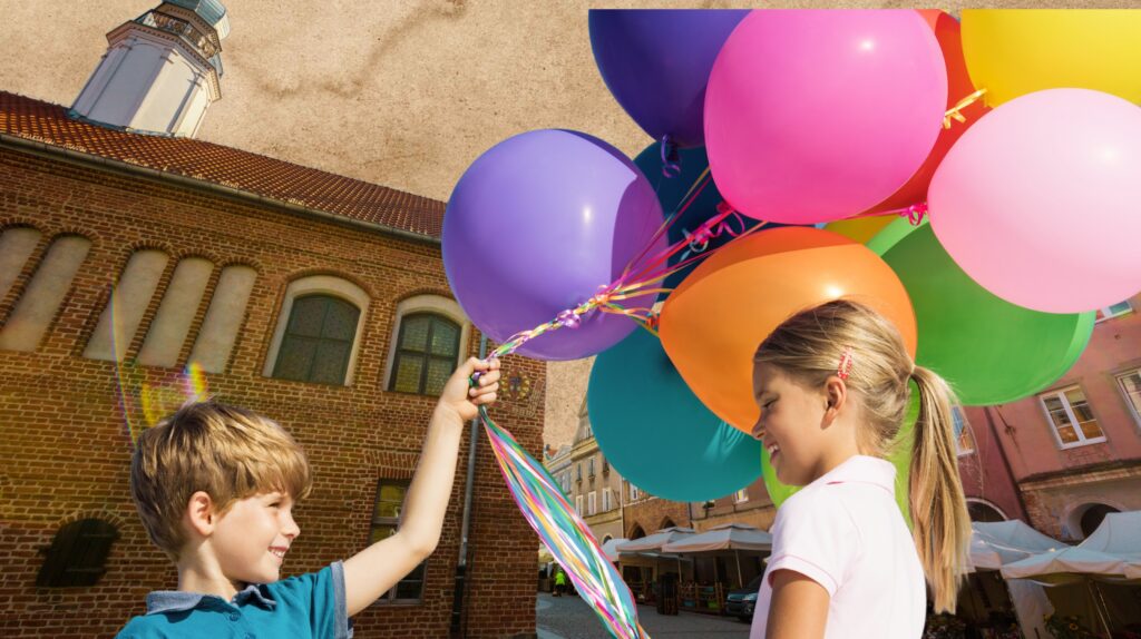 Dzieci trzymają balony w plenerze.