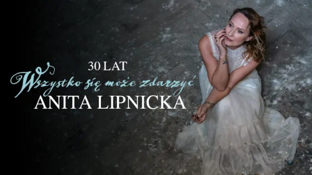 Anita Lipnicka w zwiewnej białej sukni siedząca na surowej posadzce, patrzy w górę obok stylizowanych napisów jubileuszowych.
