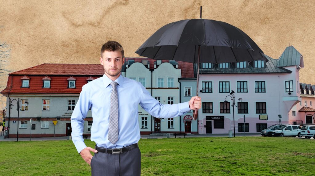 Mężczyzna w koszuli trzyma czarny parasol przed kolorowymi budynkami.