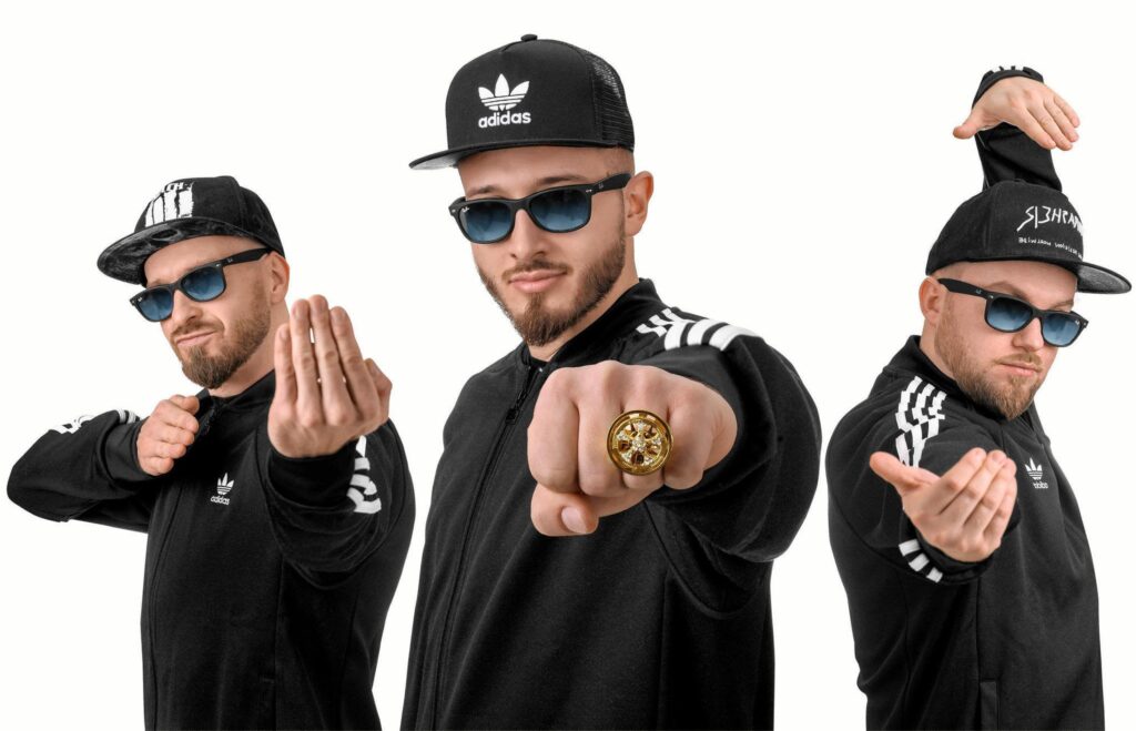 Mężczyzna w czarnej bluzie i czapce, prezentujący gesty.