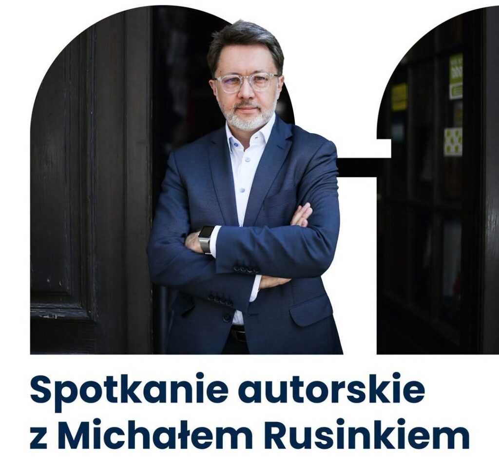 Mężczyzna w okularach stoi z założonymi rękami.