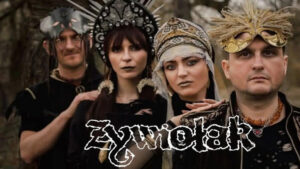 Czterech członków zespołu Żywiołak w mrocznych, słowiańskich i stylizowanych maskach oraz nakryciach głowy na tle lasu.
