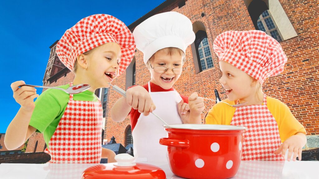 Trzy dzieci w kuchennych fartuchach gotują razem.