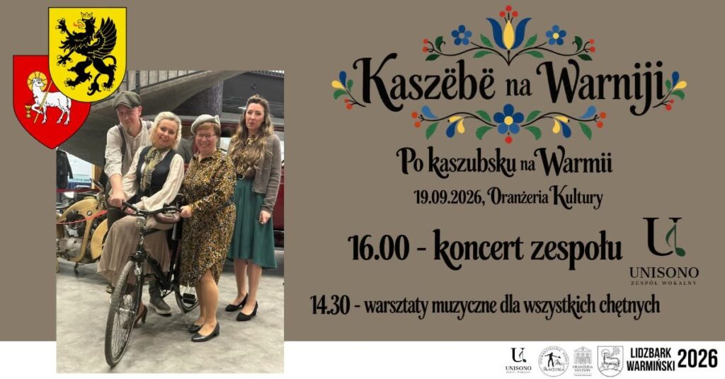 Grupa ludzi pozująca przy rowerze na tle wydarzenia kulturalnego.
