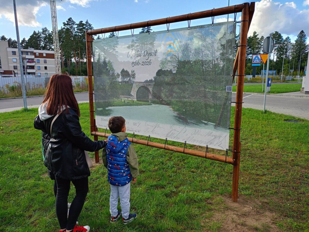 Kobieta z dzieckiem oglądają wystawę na zewnątrz.