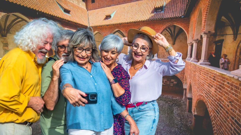 Grupa uśmiechniętych osób robi selfie w historycznym otoczeniu.