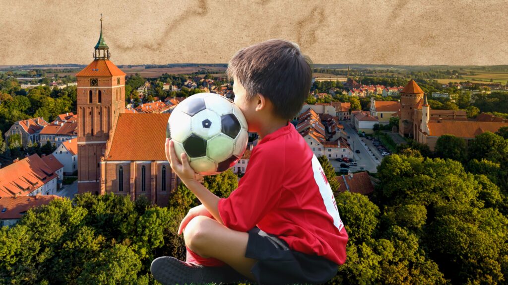 Chłopiec trzymający piłkę nożną z widokiem na miasto.