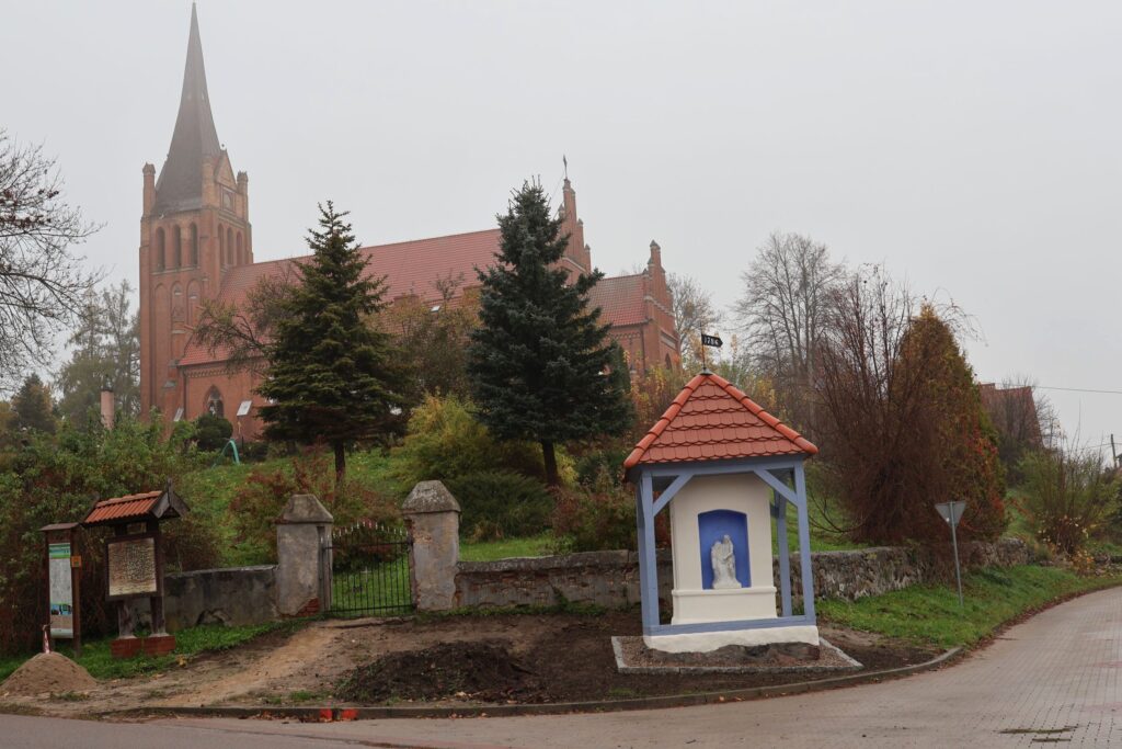 Widok na kościół z wieżą i kapliczką.
